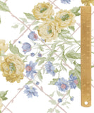 Watercolor floral wallpaper pattern featuring yellow peonies, blue forget-me-nots, and green leaves on a white background with a diagonal lattice design, shown next to a wooden ruler for scale.