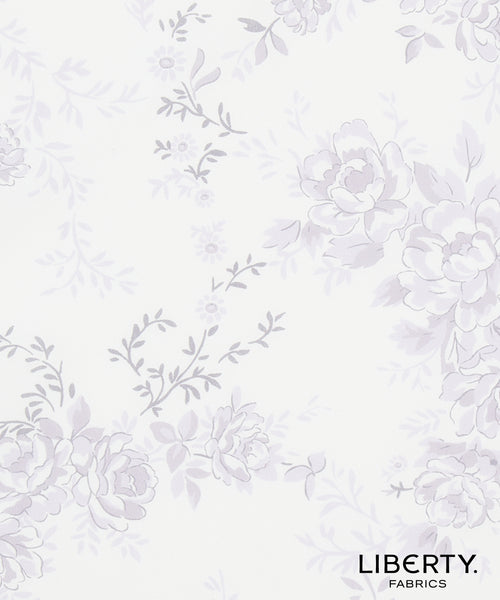 Liberty Fabrics floral pattern fabric swatch featuring light lavender and gray floral motifs on a warm off-white background, with the Liberty Fabrics logo in the bottom right corner.