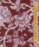A close-up of a floral fabric pattern with large mauve and lavender flowers on a deep burgundy background, shown next to a gold metal ruler for scale.