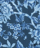 A close-up of Liberty Fabrics floral patterned fabric featuring light blue and white flowers and leaves on a dark navy blue background.