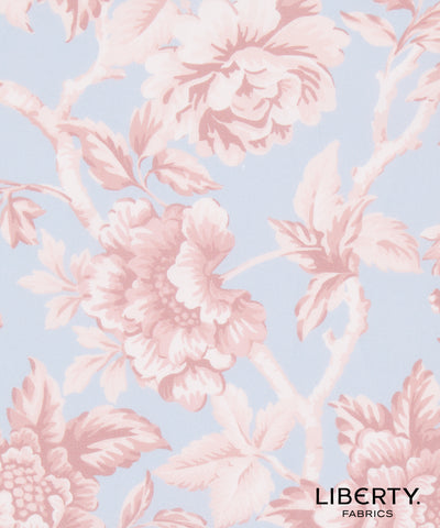 A close-up of a floral fabric pattern featuring pale pink peony-like flowers and leaves on a light blue background, with the text 'LIBERTY. FABRICS' in the lower right corner.