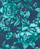 A close-up of a floral fabric pattern featuring large peony-like flowers and leaves in bright turquoise and light aqua on a dark navy blue background. The word 'LIBERTY' appears in the lower right corner, indicating the brand Liberty Fabrics.