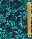 A close-up of a floral fabric pattern in teal and turquoise on a dark navy background, with a wooden ruler running vertically along the right side for scale.