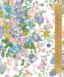 A close-up of a floral fabric pattern with blue, pink, purple, and green flowers on a white background, with a wooden ruler along the right edge for scale.
