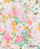 A close-up of Liberty Fabrics floral pattern featuring watercolor-style pink, lavender, teal, and orange flowers with green leaves on a white background, with the Liberty Fabrics logo in the bottom right corner.