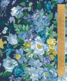 A close-up of a floral fabric pattern with blue, purple, white, and yellow flowers on a dark navy background, with a wooden ruler on the right side for scale.