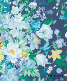 A close-up of a floral fabric print featuring white, light blue, and yellow flowers with green leaves on a dark navy blue background. The Liberty Fabrics logo is visible in the bottom right corner.