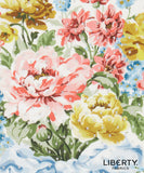 A floral fabric print featuring large pink and yellow flowers with green leaves on a white background, with the Liberty Fabrics logo in the bottom right corner. 
