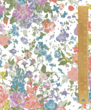 A close-up of a white fabric with a dense, multicolor floral print featuring pink, purple, blue, and green flowers, overlaid with a wooden ruler on the right side for scale.